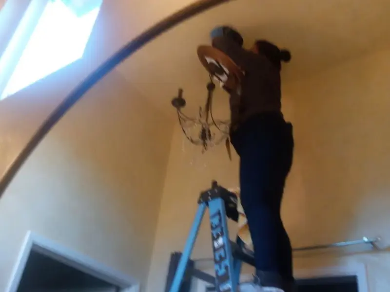 Electrician installing a chandelier in a Fulshear residence
